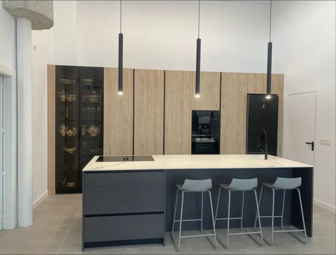 Cocina con isla gris grafito, columnas de madera y vitrina