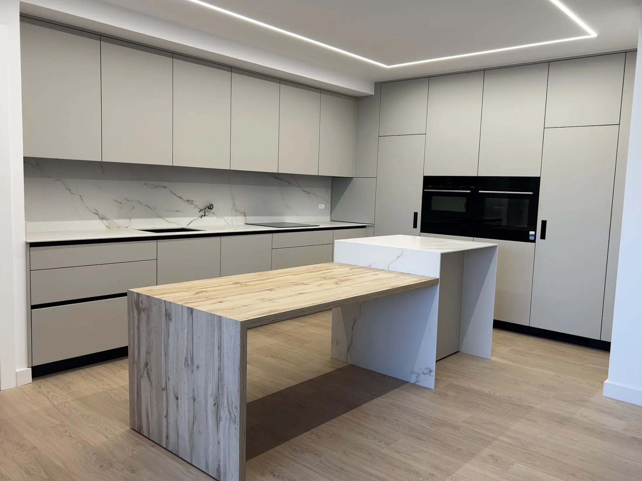 Cocina blanca con isla de madera y encimera de porcelánico, hecha a medida por Mobidesk