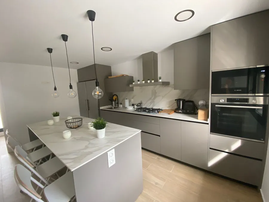 Cocina gris topo con isla blanca y lámparas colgantes